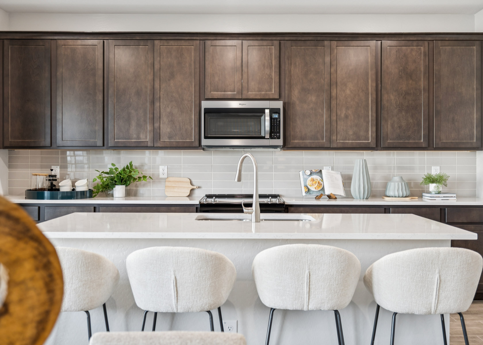 A kitchen with a white countertop and white chairs.