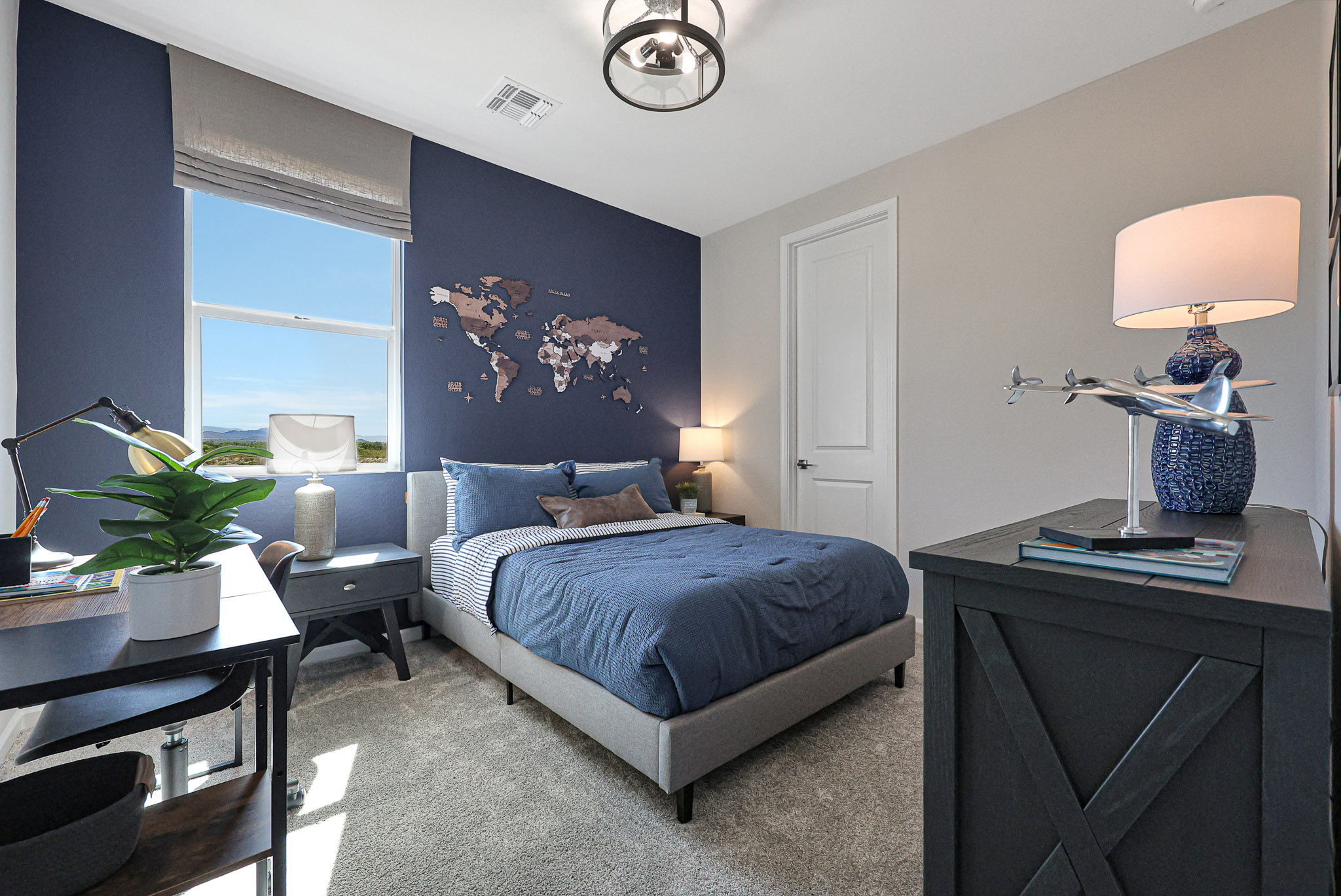 A bedroom with a bed desk and a lamp.