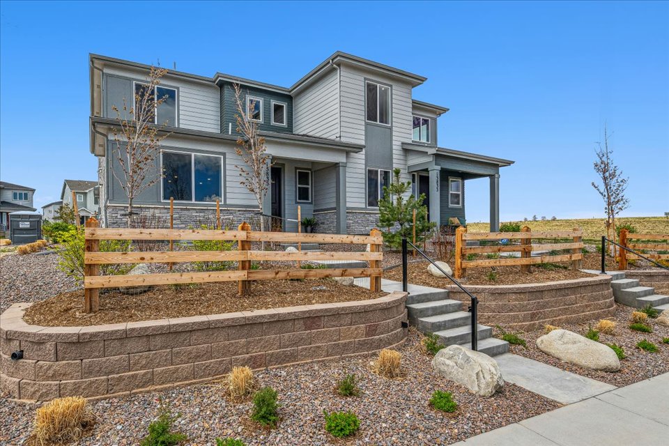 A house with a fence and a yard with a stone wall.
