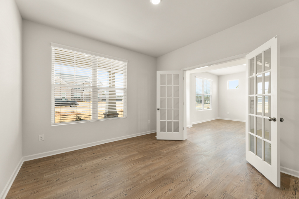 A room with a wood floor and a window with a view of the water.