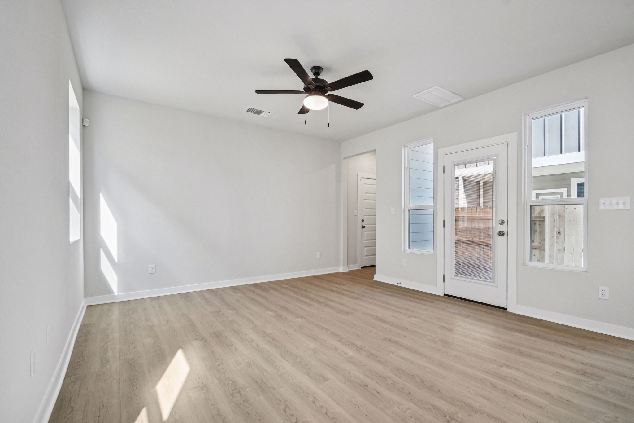 A room with a ceiling fan and a wood floor.
