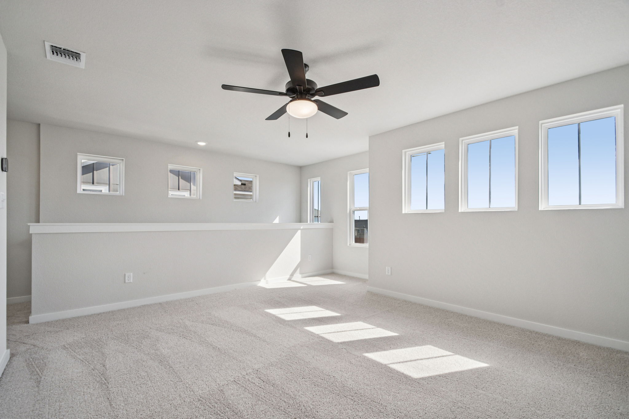 A room with a ceiling fan and a white wall with a light.