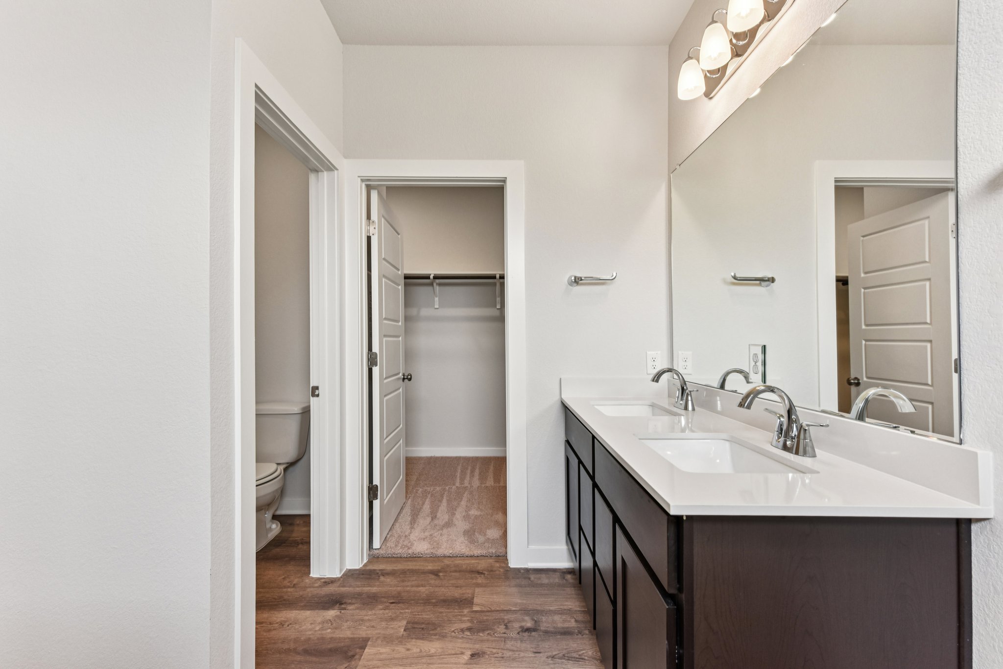A bathroom with a sink toilet and mirror.