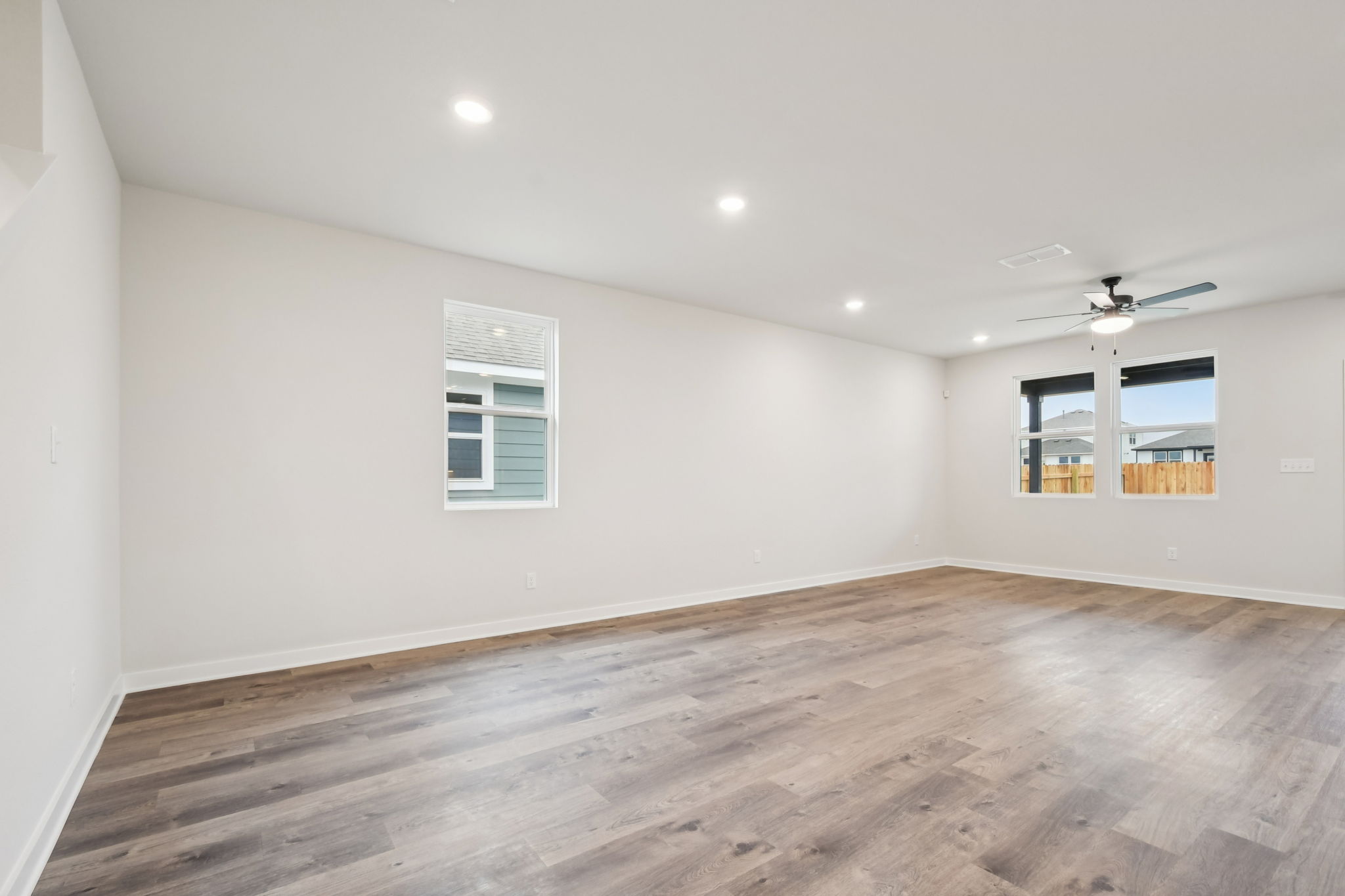 A room with a wood floor and a wood floor with a ceiling fan.