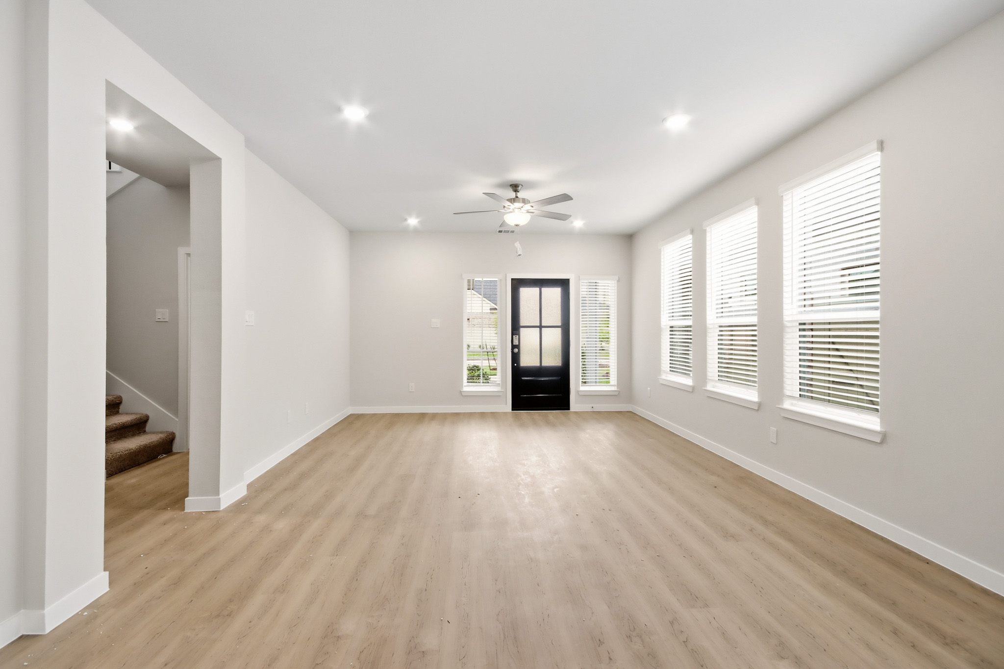 A large empty room with a wood floor and a ceiling fan.