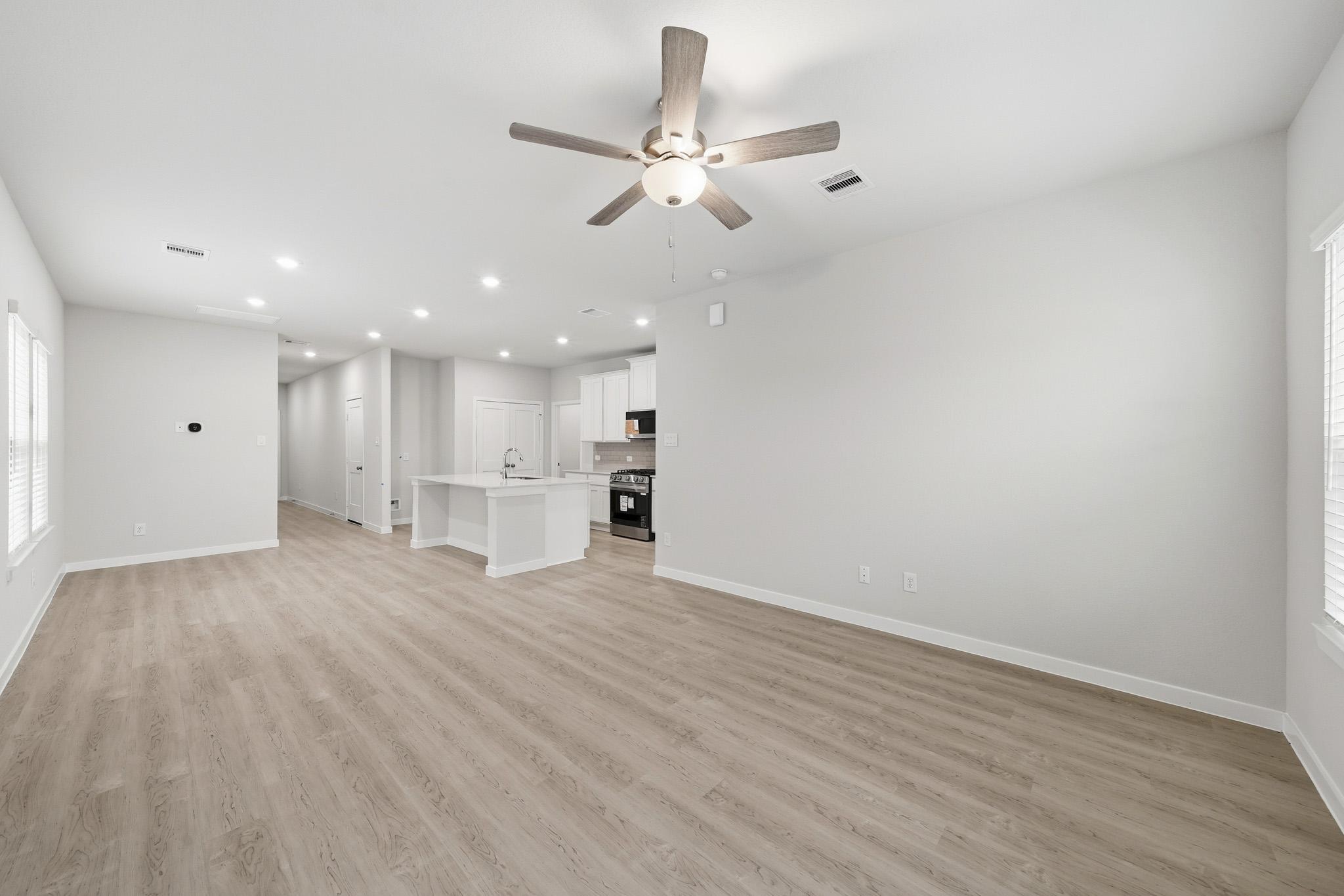 A large empty room with a ceiling fan and a wood floor.