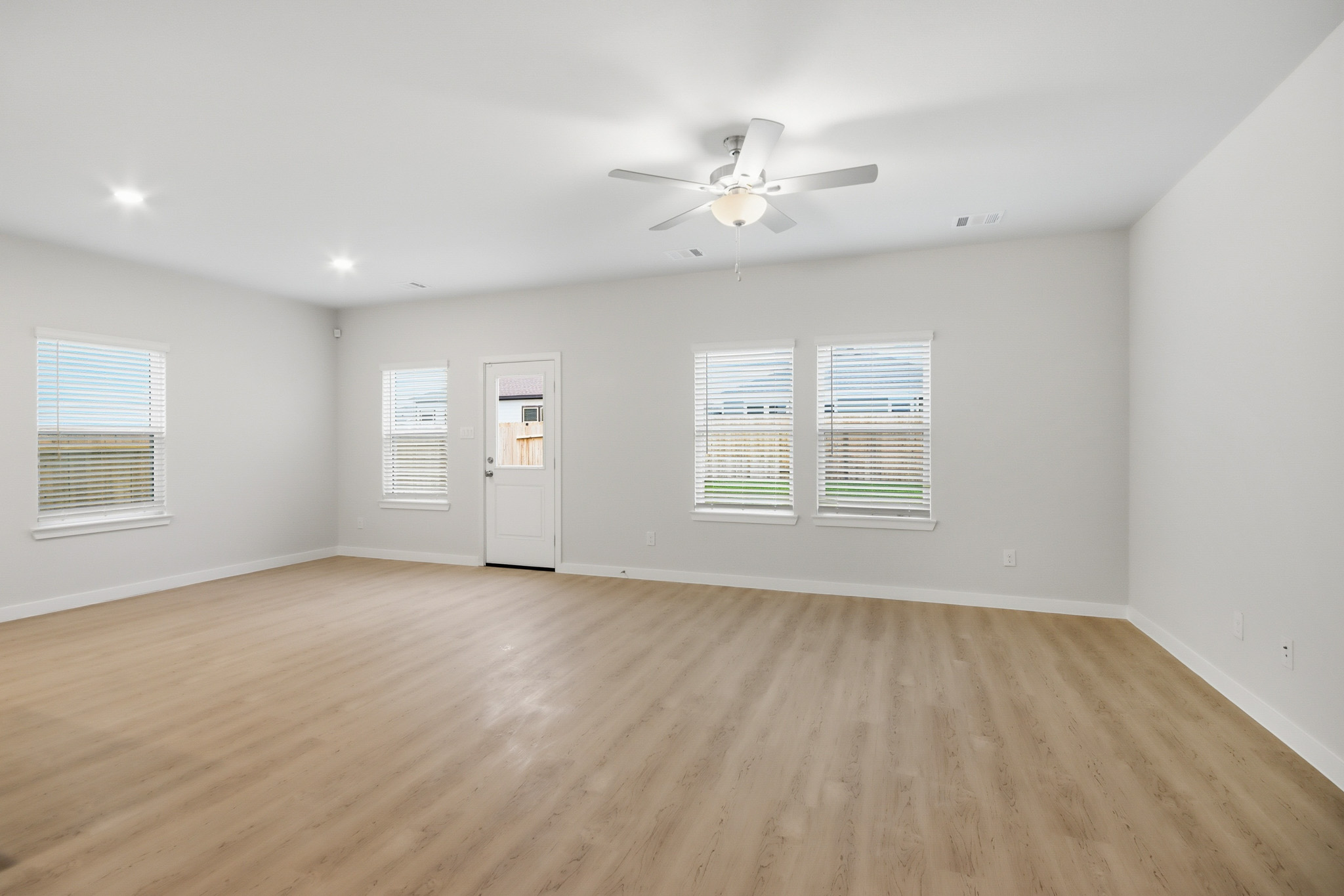 A room with a ceiling fan and a wood floor.
