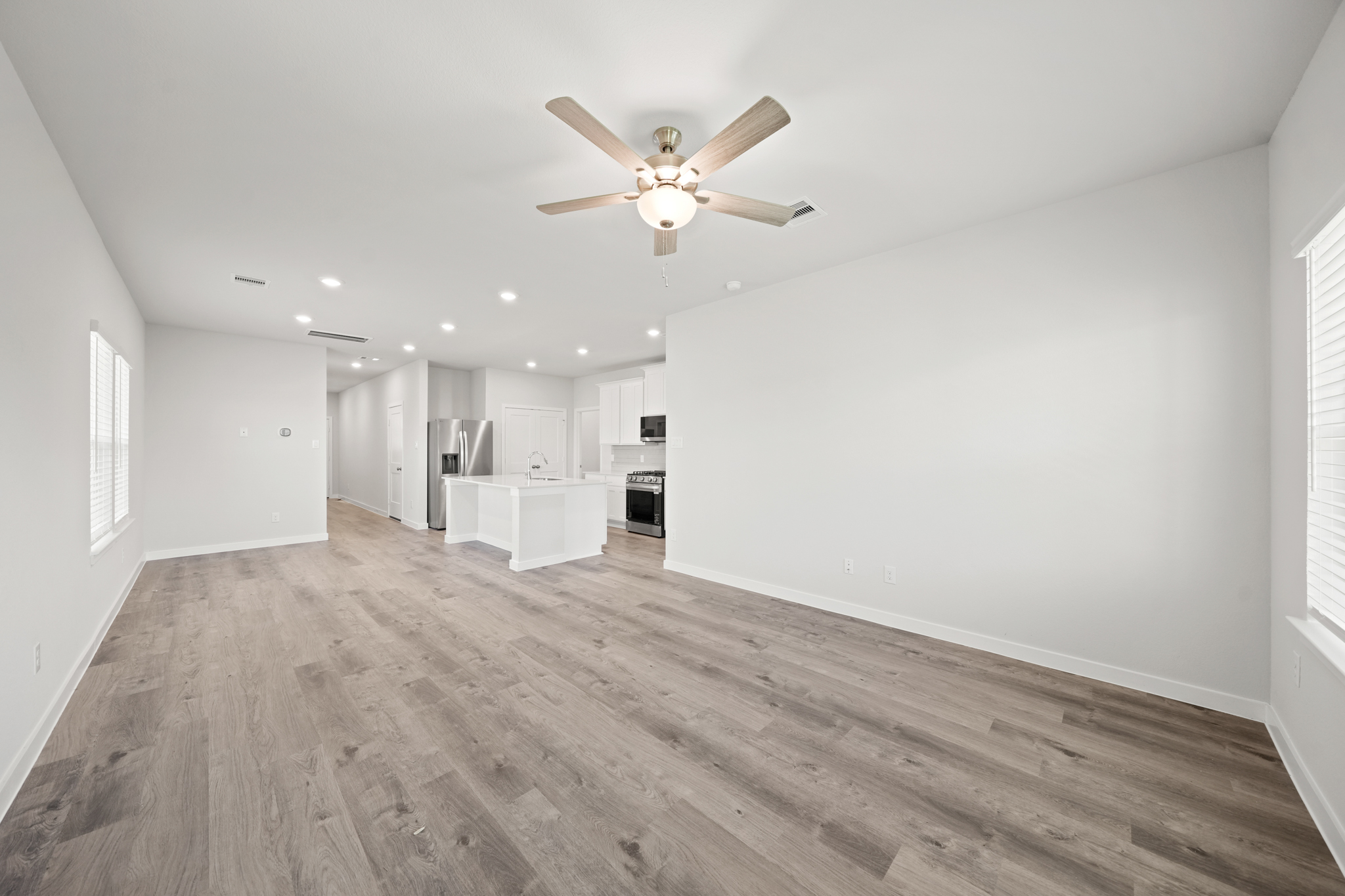 A large empty room with a ceiling fan and a wood floor.