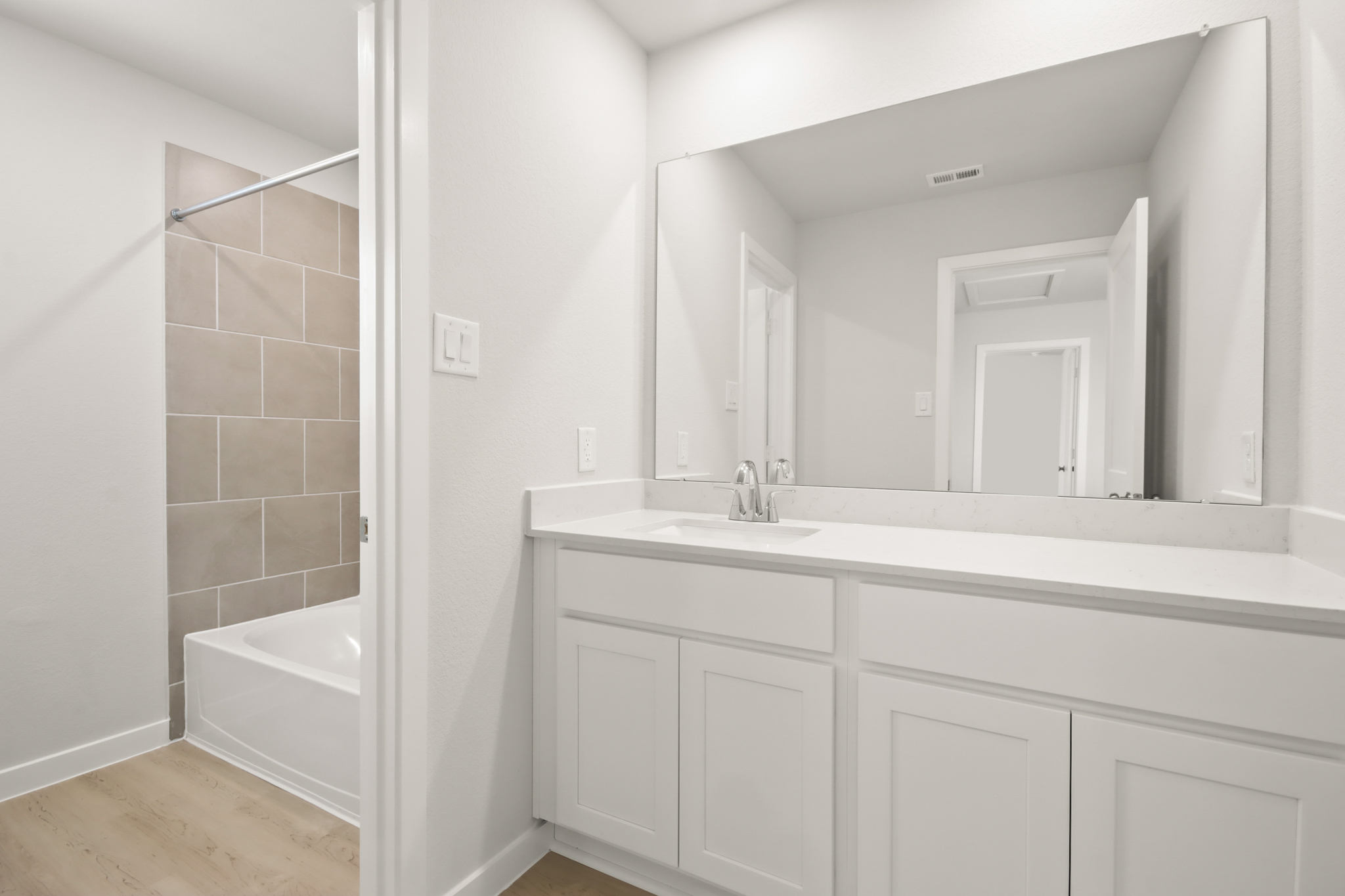 A bathroom with a tub sink and mirror.