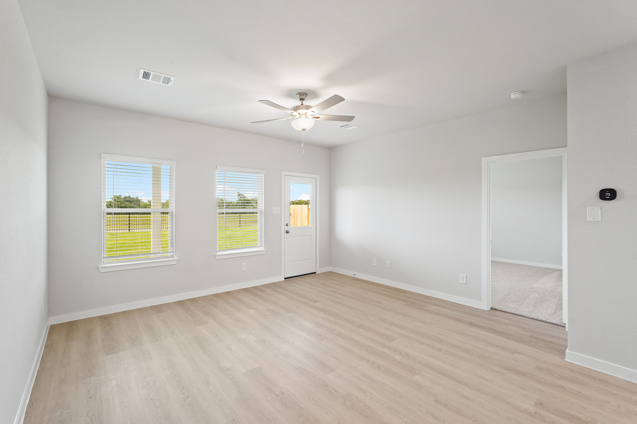 A room with a wood floor and a ceiling fan.