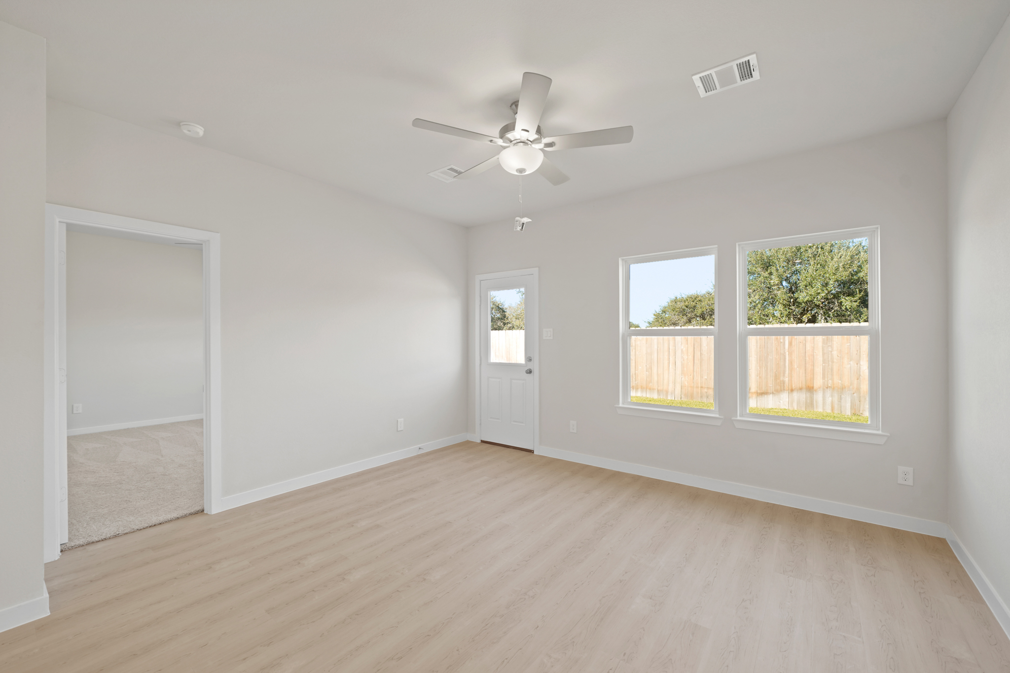 A room with a wood floor and a ceiling fan and a wood floor.