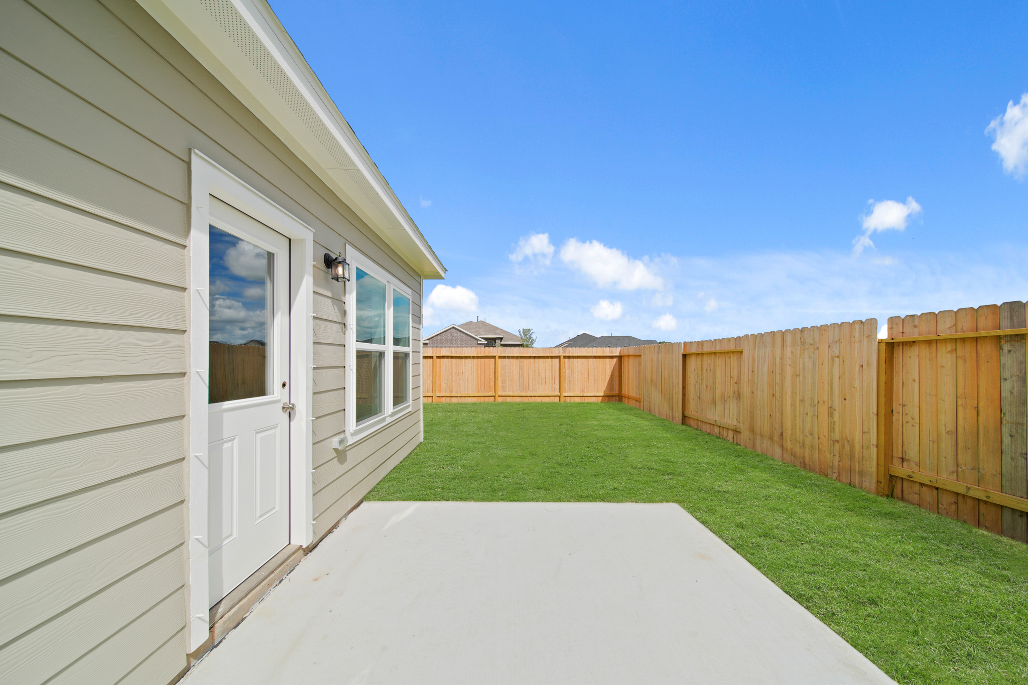 A backyard with a fence and a house.