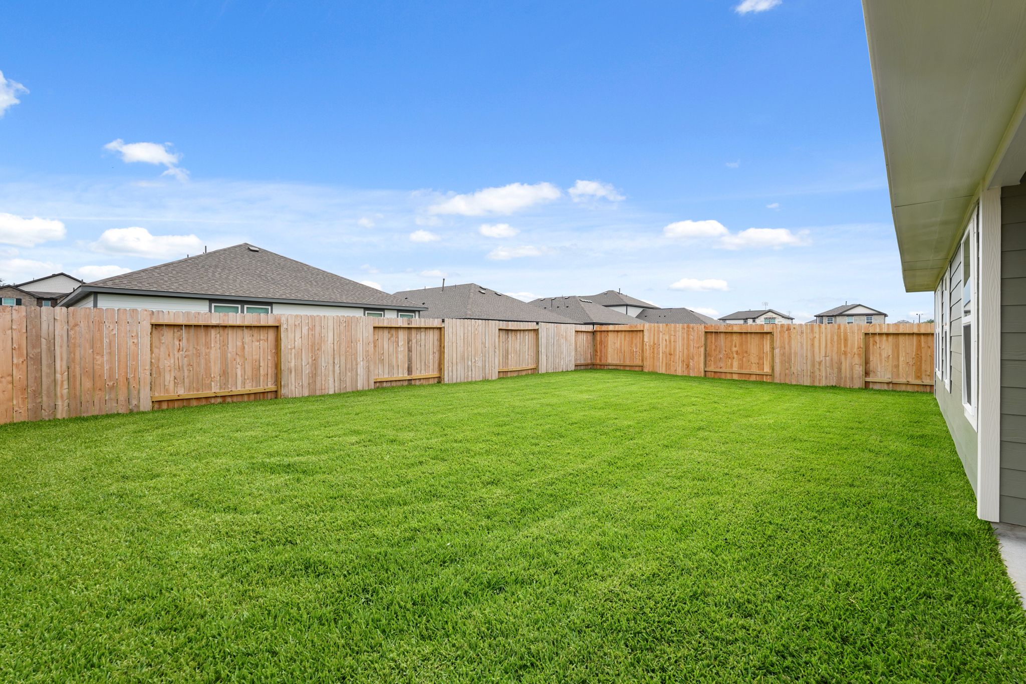 A fenced in yard with a house in the background.