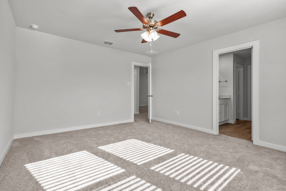 A room with a ceiling fan and a rug.
