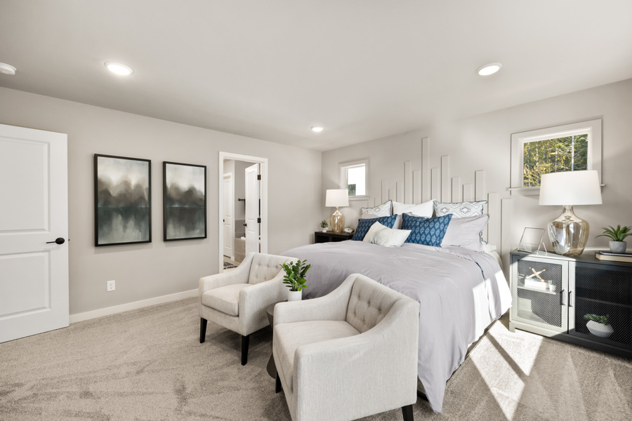 A bedroom with a bed and chairs.