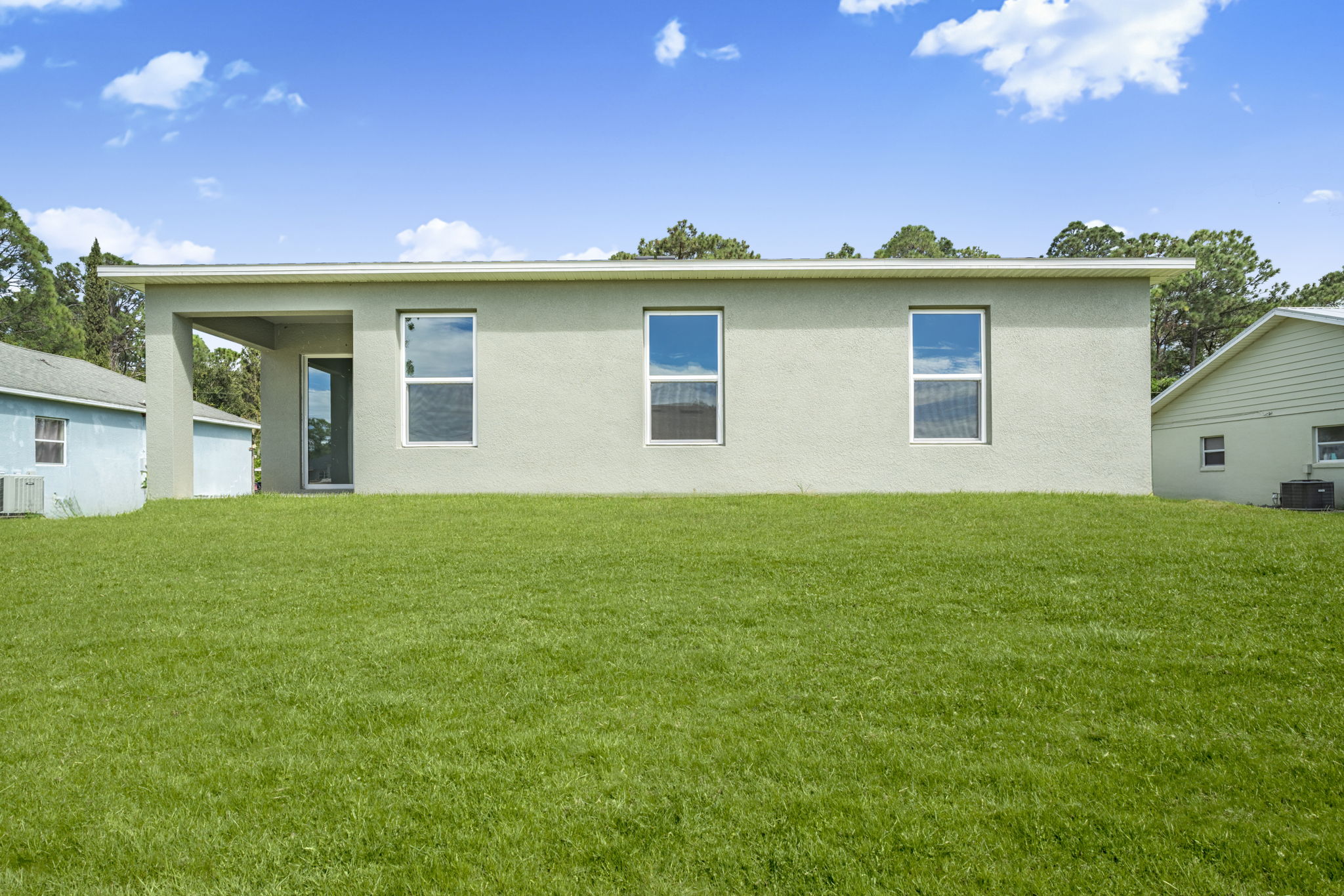 A large green lawn in front of a white house.
